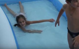 Boy wearing black speedo in a swimming pool with girl